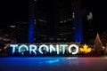 TORONTO, CANADA - 2018-01-01: People in front of TORONTO sign with Christmas tree in the night viewed across the skating