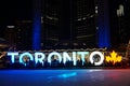 TORONTO, CANADA - 2018-01-01: People in front of TORONTO sign with Christmas tree in the night viewed across the skating