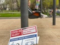 TORONTO, ONTARIO, CANADA - APRIL 26, 2021: CHILD ON SWING WITH COVID-19 ALERT SIGN ON POLE IN FRONT OF HER.