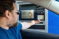 Toronto, Ontario, Canada - June 20, 2020: Caucasian bearded man taking cash money from ATM machine at drive through bank. Driver