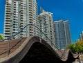 great view of a wavy wooden bridge with modern residential condo buildings in background