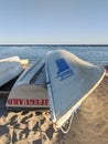 Toronto, Ontario, Canada - Sep 11, 2020: White canoe with Toronto logo and sign next to a lifeguard board turned upside down