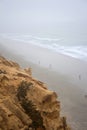 Torrey Pines State Reserve, La Jolla, California ocean view from cliff top with people walking on beach below on cloudy day