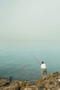 A local fisherman casting his fishing rod into the Mediterranean sea on the rocks off the coast of Torrox Royalty Free Stock Photo