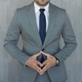 Torso of anonymous businessman standing with hands in lowered steeple wearing beautiful fashionable classic grey suit Royalty Free Stock Photo