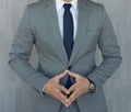 Torso of anonymous businessman standing with hands in lowered steeple wearing beautiful fashionable classic grey suit Royalty Free Stock Photo