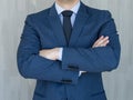 Torso of a businessman standing with folded arms in a classic navy blue suit.