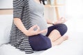 Torso close-up of pregnant woman working out indoors. Pregnant fitness woman sitting in yoga crossed-leg pose . Royalty Free Stock Photo