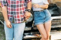 torso of a pair that is leaning on the car and holding hands in the summer. in the hands of a flower girl, on the hand of a guy we Royalty Free Stock Photo