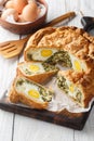 Torta Pasqualina traditional Italian savory pie with spinach, chard, ricotta and whole eggs closeup on the wooden board. Vertical