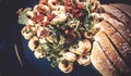 Tortellini salad with mushrooms, dried tomatoes, arugula and herbs - In addition, home-baked Parmesan roll - Shallow depth of Royalty Free Stock Photo