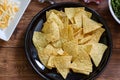 Tortilla chips on a black crockery with various vegetables and minced meat on a wooden table Royalty Free Stock Photo