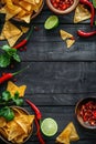 Tortilla chips with red hot chili peppers, lime, and salsa dip on wooden background Royalty Free Stock Photo