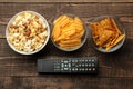 Tortilla popcorn, chips and TV remote on a brown wooden background. concept of watching movies at home. view from above Royalty Free Stock Photo