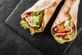 Tortilla wraps with grilled chicken, fresh vegetables and salad on black stone background. Healthy snack or take-away lunch. Royalty Free Stock Photo