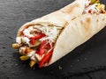 Tortilla wraps with grilled chicken, fresh vegetables, salad, potatoes on black stone background. Healthy snack or take-away lunch Royalty Free Stock Photo