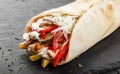 Tortilla wraps with grilled chicken, fresh vegetables, salad, potatoes on black stone background. Healthy snack or take-away lunch Royalty Free Stock Photo