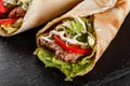 Tortilla wraps with grilled meat, fresh vegetables and salad on black stone background. Healthy snack or take-away lunch Royalty Free Stock Photo