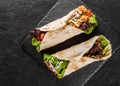 Tortilla wraps with grilled meat, fresh vegetables and salad on black stone background. Healthy snack or take-away lunch. Top view Royalty Free Stock Photo