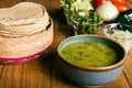 Tortillas, bowl with green sauce and vegetables on a wooden table.