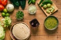 Tortillas, bowl with green sauce and vegetables on a wooden table.