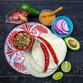 Tortillas flat and various vegetables for tacos or burrito making on rustic background, top view, border chef cooking mexican