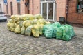 Plastic bags with segregated garbage on the street. Yellow plastic bags and green ones with glass