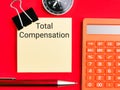 Total compensation written on sticky note with a pen,compass and calculator. Royalty Free Stock Photo