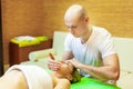 Total relaxation. Beautiful young woman lying on her back while professional massage therapist massaging her face