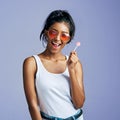 Totally carefree. Studio portrait of a beautiful young woman sucking on a lollipop against a purple background. Royalty Free Stock Photo