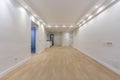 Totally empty living room with white painted walls with a wooden floor, integrated ceiling lights, a corridor leading to other Royalty Free Stock Photo