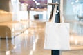 Tote bag canvas fabric for mockup blank template, hanging on a doorknob in the meeting room in the office with blur background