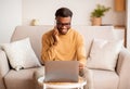 Afro Man Using Laptop Having Pleasant Phone Conversation At Home Royalty Free Stock Photo