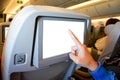 Close up of a man pointing finger to white blank LCD screen monitor behind passenger seat in the economy class Royalty Free Stock Photo