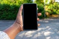 Touch screen mobile phone, in African woman`s hand. Black Female holding smart phone on green outdoor background with blank copy s Royalty Free Stock Photo