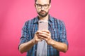 Always in touch. Serious young man holding smart phone and looking at it. Portrait of a happy young man using mobile phone