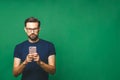 Always in touch. Smiling young man holding smart phone and looking at it. Portrait of a happy man using mobile phone isolated over Royalty Free Stock Photo