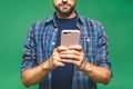 Always in touch. Smiling young man holding smart phone and looking at it. Portrait of a happy man using mobile phone isolated over Royalty Free Stock Photo