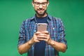 Always in touch. Smiling young man holding smart phone and looking at it. Portrait of a happy man using mobile phone isolated over Royalty Free Stock Photo