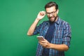 Always in touch. Smiling young man holding smart phone and looking at it. Portrait of a happy man using mobile phone isolated over Royalty Free Stock Photo