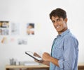 Touch technology. An ethnic businessman working on his digital tablet and smiling at the camera. Royalty Free Stock Photo