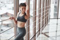 Touching the hair. Brunette girl in sportswear posing and laying on railings near window in the gym Royalty Free Stock Photo