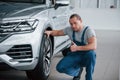 Touching the wheel. After professional repairing. Man looking at perfectly polished silver colored car