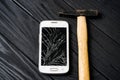 Touchscreen of a smartphone is broken with a hammer on the grey wooden background Royalty Free Stock Photo