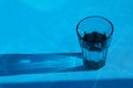 Tough, abstract shadow from a transparent glass with drinking water on a blue background. Selective focus, copy space Royalty Free Stock Photo