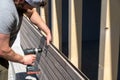 Tough construction worker applies wooden siding to a garage and drills screws