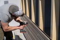 Tough construction worker applies wooden siding to a garage and drills screws