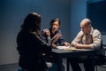 A tough police detective interrogates a crime suspect with a tattooed face in an interrogation room. Royalty Free Stock Photo