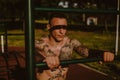 Tough tattooed man leaning on the workout bar outside