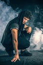 Tough young man in dark t-shirt on grey background